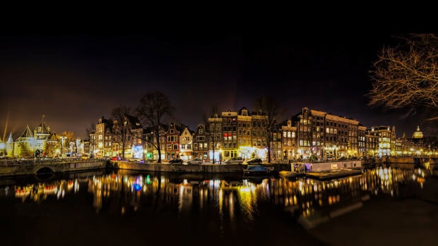 Nighttime canal view with tall buildings and trees in Netherlands cityscape