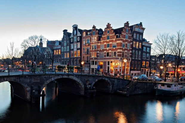 Historic street architecture in Netherlands during twilight with canal and bridge