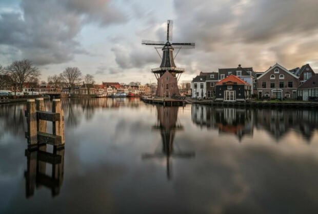 Historic windmill and traditional houses by the canal in Netherlands town