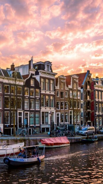 Traditional Amsterdam canal houses along the waterway in Netherlands at sunset