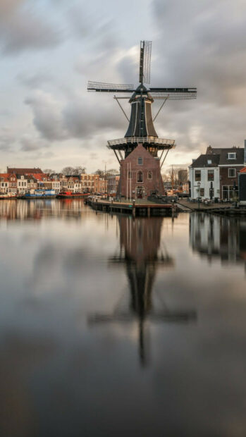Traditional Dutch windmill reflecting on calm water in Netherlands cityscape