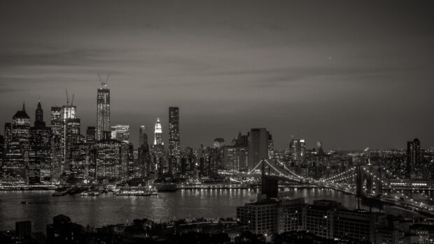 New York skyline in black and white showing iconic skyscrapers and bridge at night