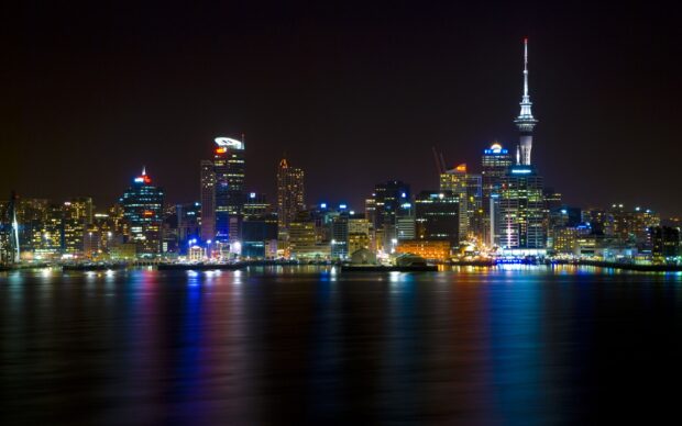 City skyline illuminated with colorful lights reflecting on calm water at night