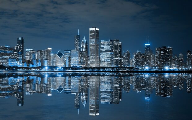Night skyline with skyscrapers reflecting on calm water at night