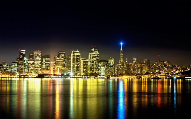 The city skyline at night with illuminated buildings and colorful reflections on the water