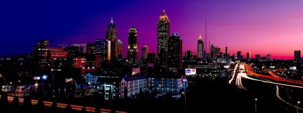 Vibrant night skyline with illuminated buildings and a glowing purple sky
