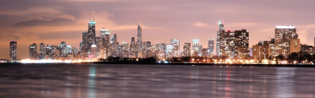 Night skyline with illuminated buildings and city lights reflecting on the calm water