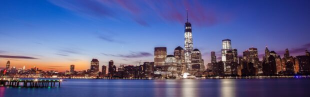 Night skyline with illuminated buildings reflecting on the water during twilight