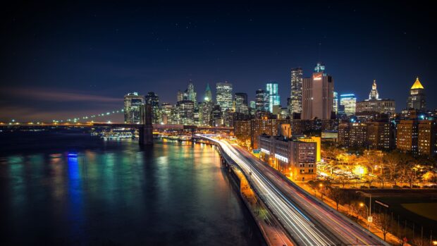 Night skyline with illuminated city buildings and a bridge over the river at night