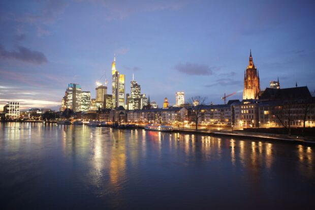 Night skyline with illuminated buildings reflects on the calm river at dusk