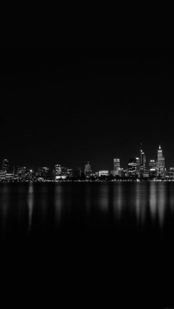 A serene night skyline with illuminated buildings reflecting over calm water
