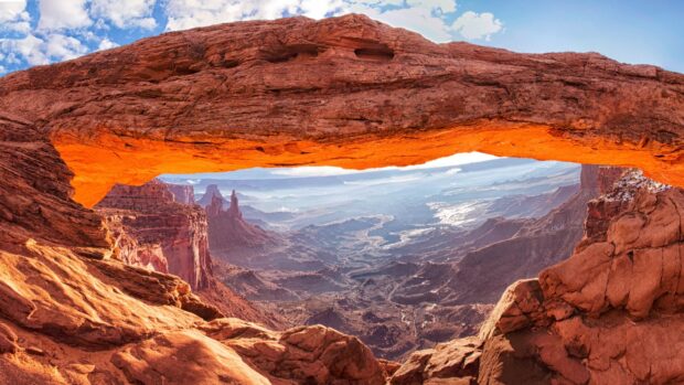 Mesa arch in North America displaying vibrant red rocks and vast canyon view