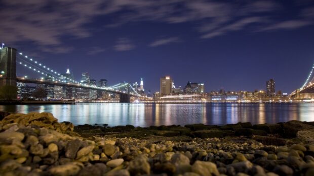 Night view of North America city skyline with illuminated bridge and river reflections