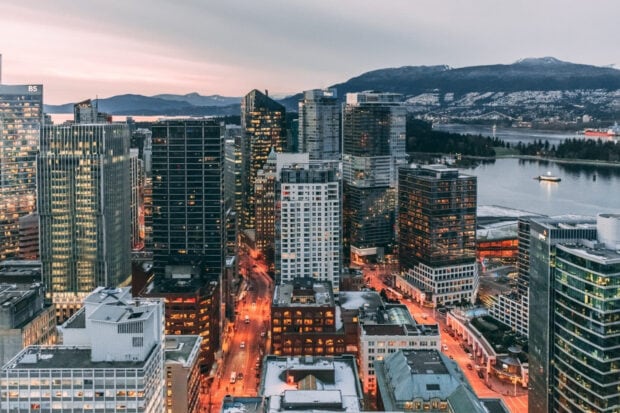 A cityscape of North America with tall buildings and a sunset sky in the background