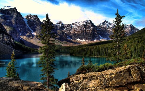 Snow capped mountains and evergreen trees surrounding a turquoise lake in North America