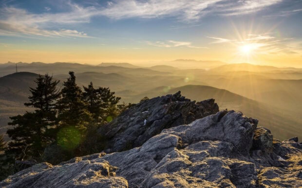 Rocky mountain landscape in North Carolina with sunrise over forested hills and trees