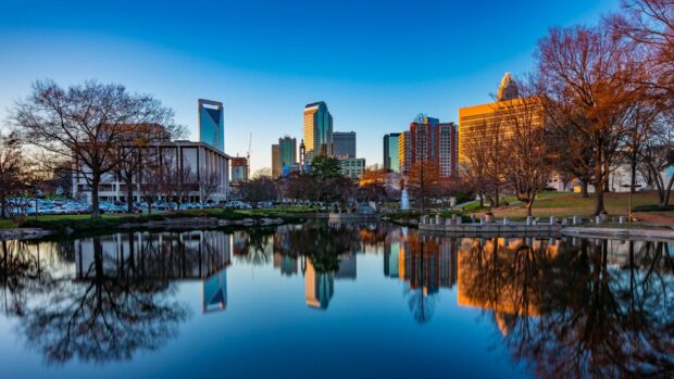 Cityscape of North Carolina skyline reflected in a calm lake during sunset