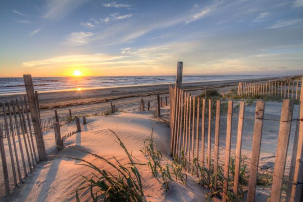Golden sunlight on sand dunes with wooden fences at the North Carolina coast