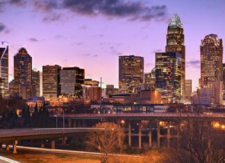 The North Carolina city skyline glows at sunset with modern buildings and highways in view