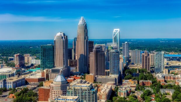 Aerial view of North Carolina city skyline with tall buildings and greenery under blue sky