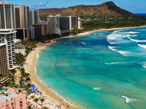 A bustling cityscape of Oahu with turquoise ocean and Diamond Head in the background