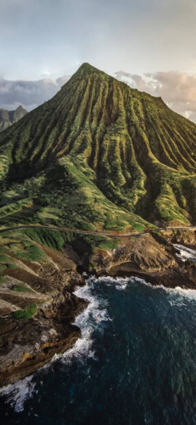Lush volcanic mountain in Oahu surrounded by ocean cliffs and waves