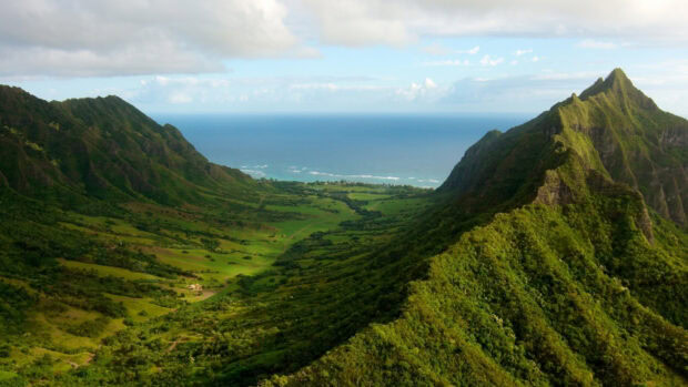 Lush green mountains and valley on Oahu with ocean in the distance