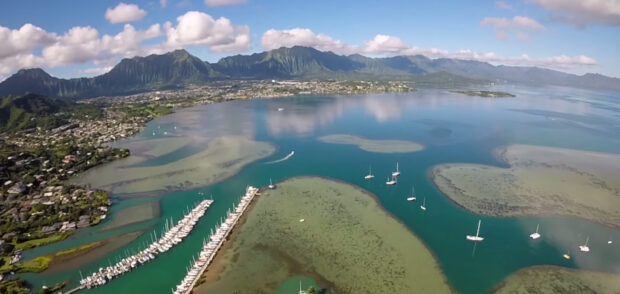Aerial view of Oahu coastline with boats and mountains in the distance
