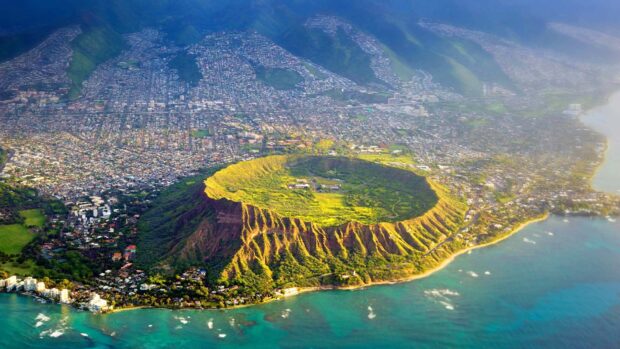 Aerial view of Oahu crater surrounded by city and ocean in bright sunlight
