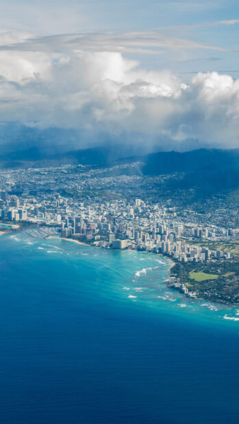 Aerial view of Oahu cityscape and coastline under a cloudy sky
