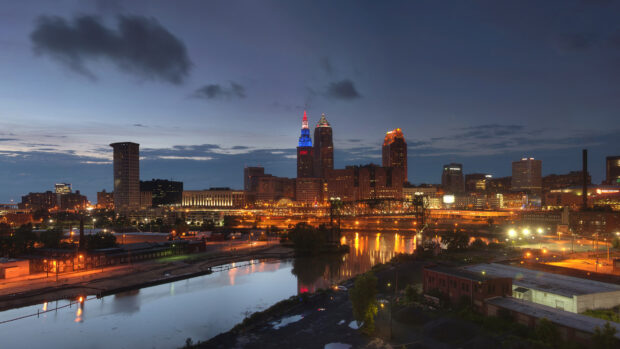 Nighttime cityscape of downtown Ohio with illuminated buildings and river reflections