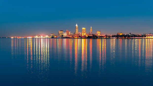 Ohio city skyline reflecting on calm lake water at night with bright lights