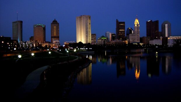 Ohio cityscape at night with illuminated buildings and river reflections