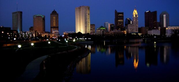 Nighttime cityscape of Ohio skyline reflecting on calm river water at dusk