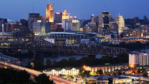 The Cincinnati skyline at dusk showcasing Ohio buildings and bridges illuminated against the night sky
