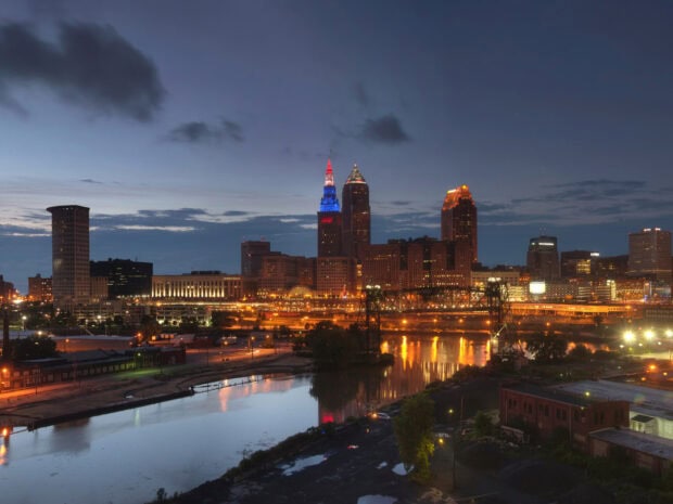 The Ohio city skyline with colorful lit buildings and river reflections at dusk