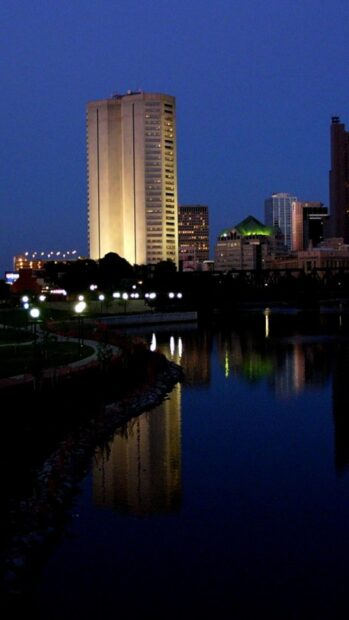 Night view of Ohio city skyline with illuminated buildings reflected in the river