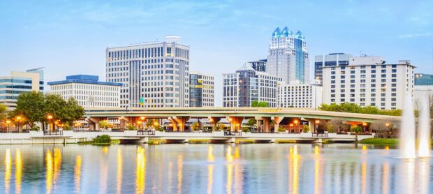 A beautiful Orlando skyline with city buildings and bridge reflected in the water at dusk