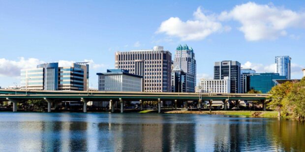 View of Orlando skyline with modern buildings reflecting on the lake and clear blue sky
