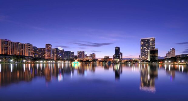 Calm Orlando skyline at dusk with city lights reflecting on water surface