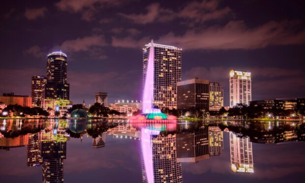 The Orlando skyline featuring a colorful fountain reflected in the lake at night