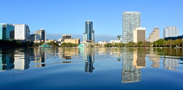 Orlando city skyline reflecting on lake water under clear blue sky