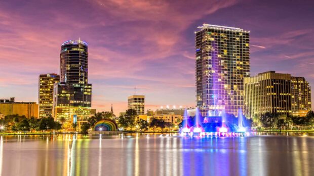 Orlando skyline at dusk with illuminated buildings and colorful fountain reflections