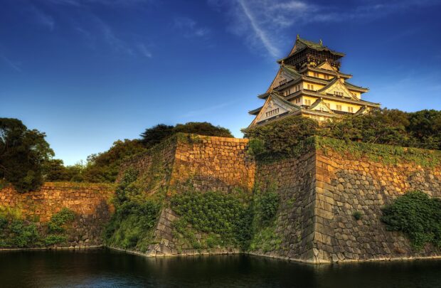 Osaka Castle surrounded by stone walls and greenery under a clear blue sky