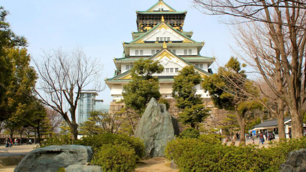 Osaka Castle is surrounded by trees and rocks in a scenic park setting