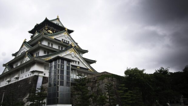 Osaka Castle stands tall with its traditional architecture under a cloudy sky in the cityscape