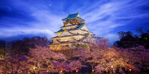 Beautiful Osaka Castle surrounded by cherry blossoms during twilight sky