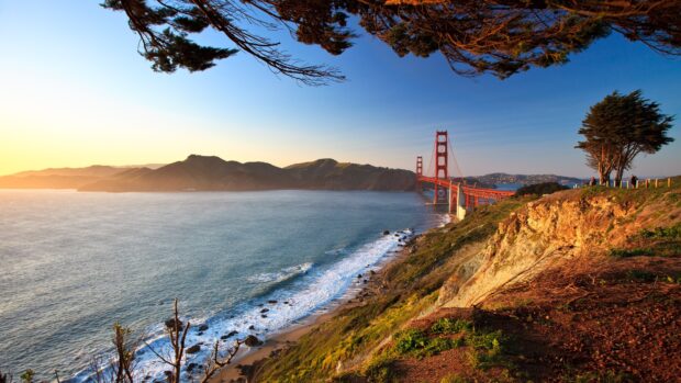 Pacific Ocean view with coastline and bridge near hills at sunset