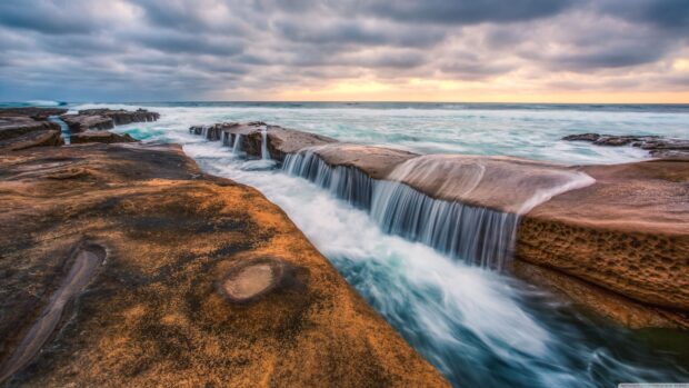 Rocky shoreline with flowing water in the Pacific Ocean at sunset