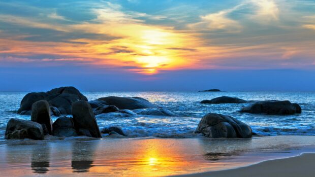 Rocky shoreline with sunset over the Pacific Ocean reflecting on the water surface
